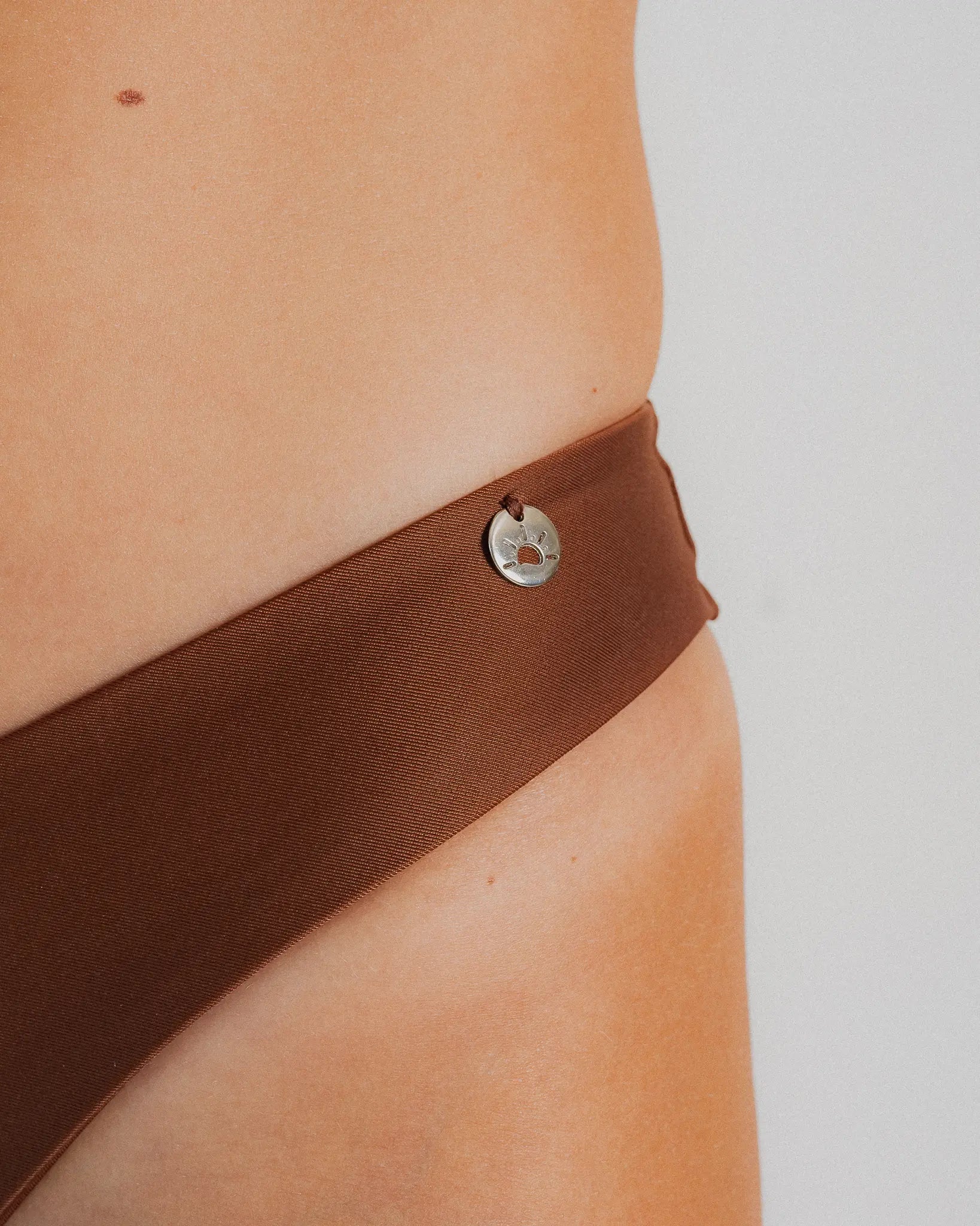 Détail médaille soleil bas maillot brésilien marron — Soleil Leblon®