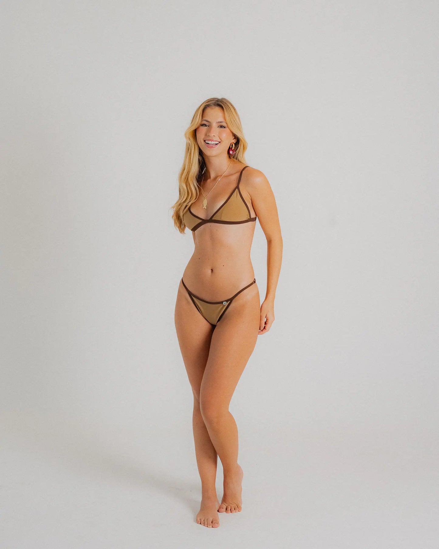 Mannequin portant un bikini deux pièces beige et marron à fines bretelles, avec détails contrastés et coupe échancrée, posé sur fond blanc minimaliste.